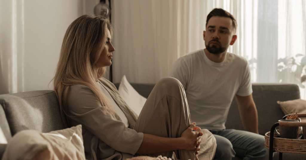 Couple sitting apart on couch showing emotional distance and tension in a relationship