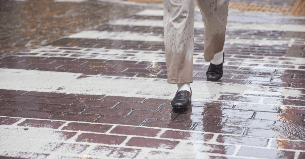 Person walking alone on a wet brick street in the rain, reflecting a quiet, heavy mood