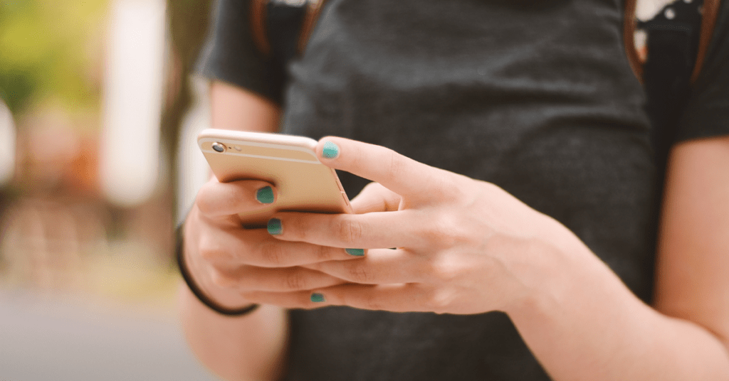 Close-up of a person holding a smartphone, representing saving or accessing mental health crisis hotline numbers for support.