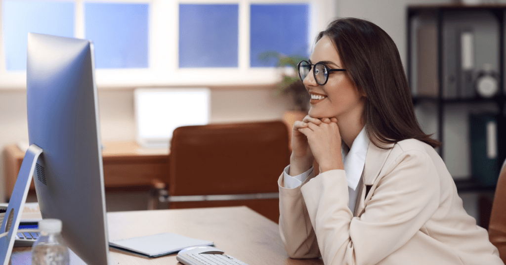 Woman smiling at computer during virtual therapy session in a modern office