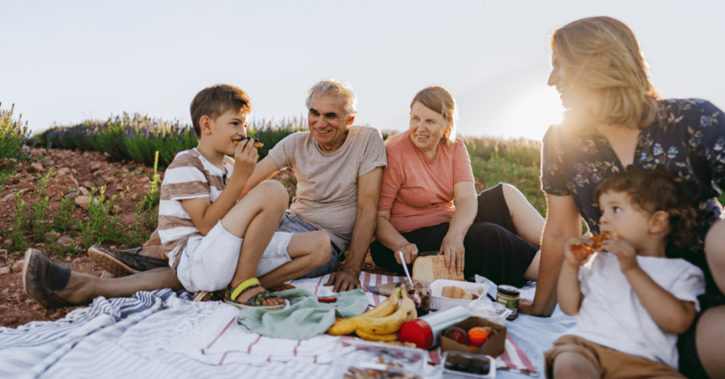 Multi-generational family spending time together outdoors during a picnic at sunset