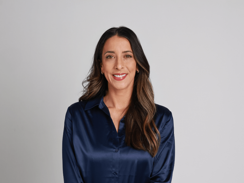 A studio photograph of Marta Hamilton, smiling in a navy silk blouse