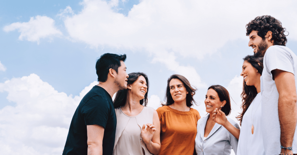 group of peers talking outside with a bright blue sky in the background
