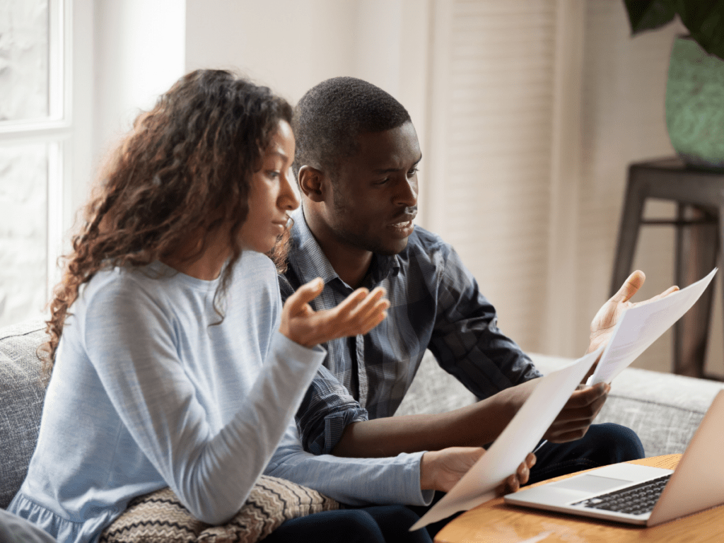 Concerned black couple read bills considering paperwork at home